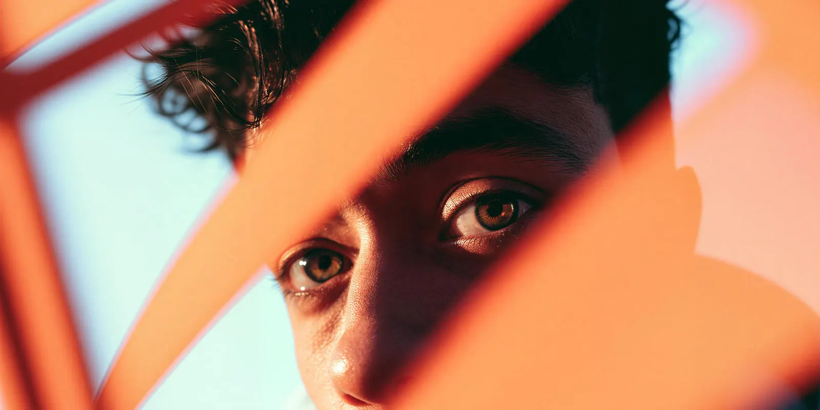 Close-up of a face crossed by bands of orange light and shadow: colored light like this shifts every shade, so swatches need neutral light