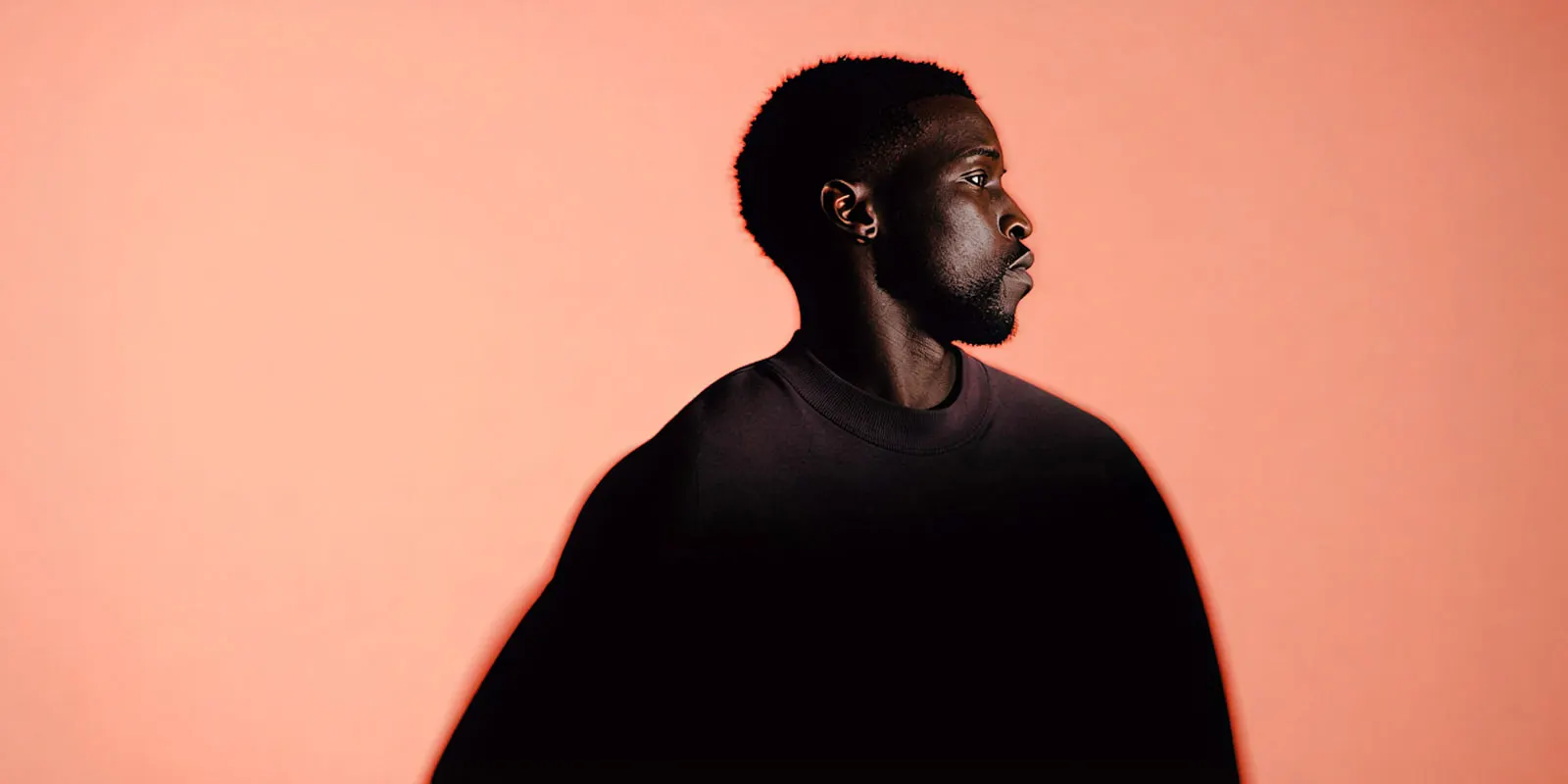 Man in side profile against a coral backdrop, a single portrait of the kind used as a reference to keep one face