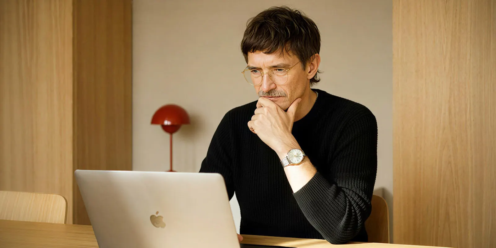 Man in a black sweater at a laptop with his hand on his chin, reviewing each image for the faults that repeat