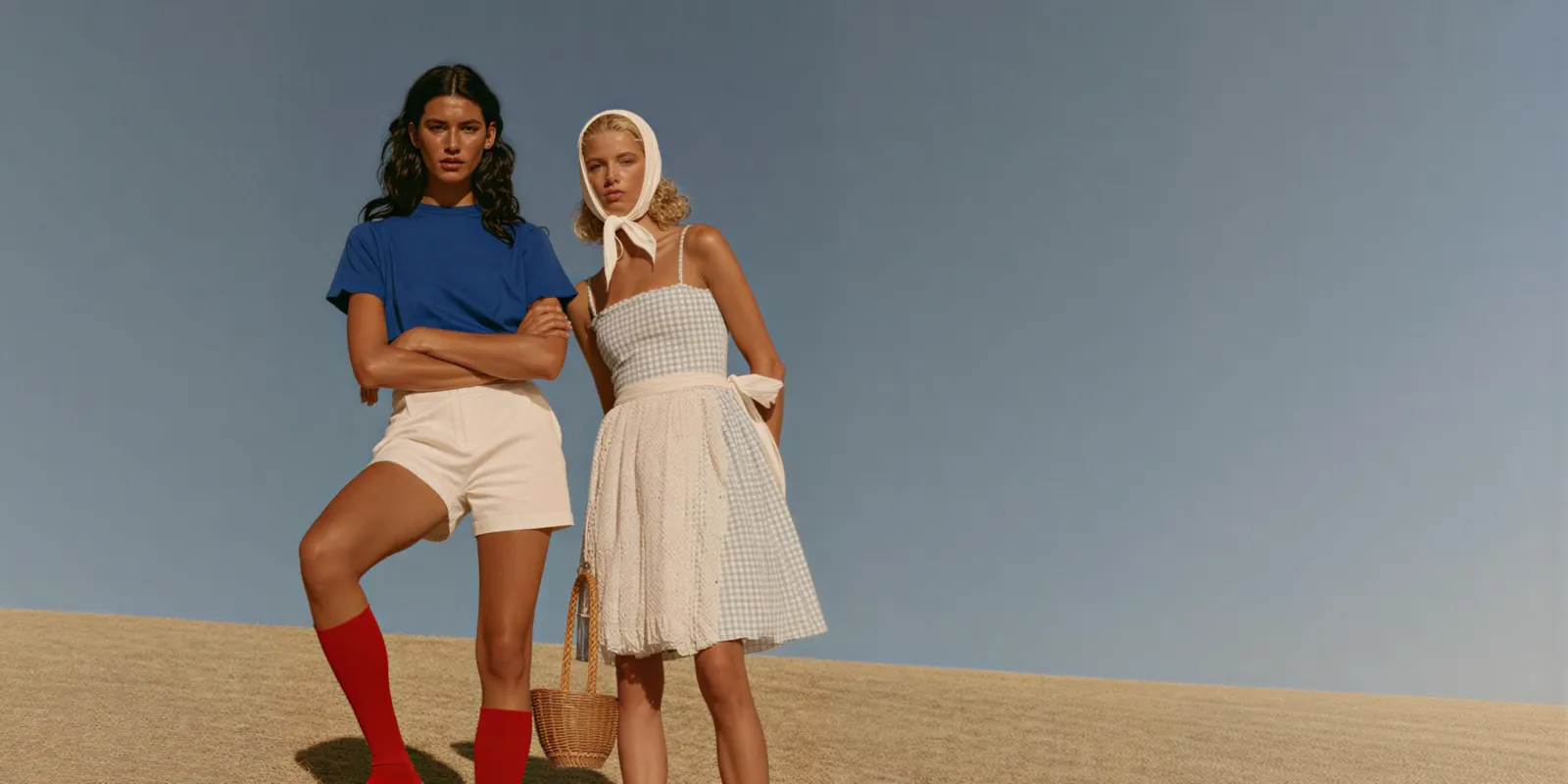 Two women posing on sand, one in a blue shirt and red socks, the kind of on-foot frame that shows where a sock sits