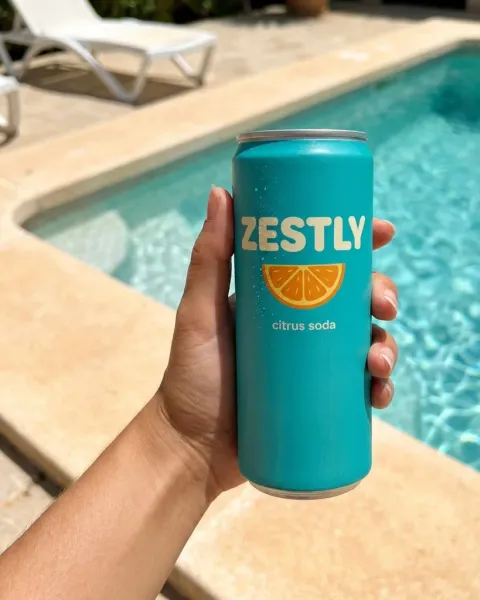 A hand holding the same can by a pool, made with DesignerBox