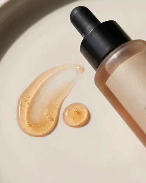 A serum bottle with a drop of oil on stone, made with DesignerBox