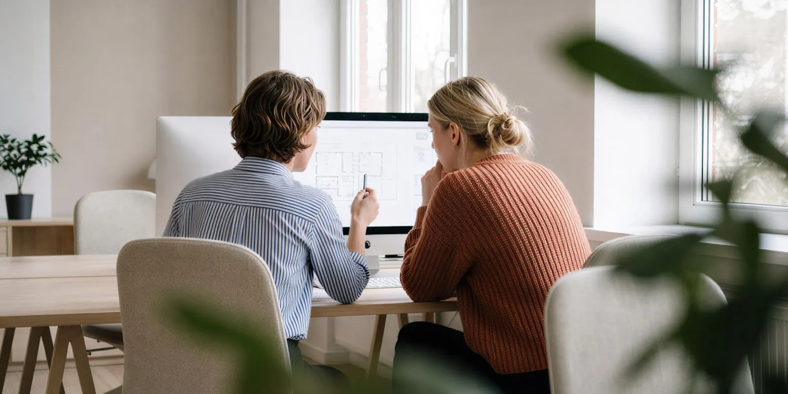 Two colleagues side by side reviewing a floor plan drawing on a monitor, the approval step that no pipeline removes