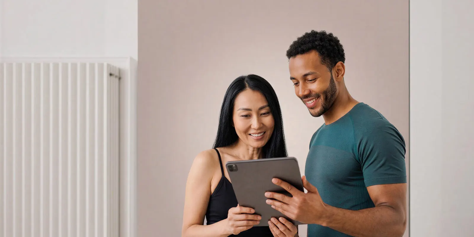 Man and woman stand together looking at a tablet in a bright room, the moment to ask a vendor for its answers in writing