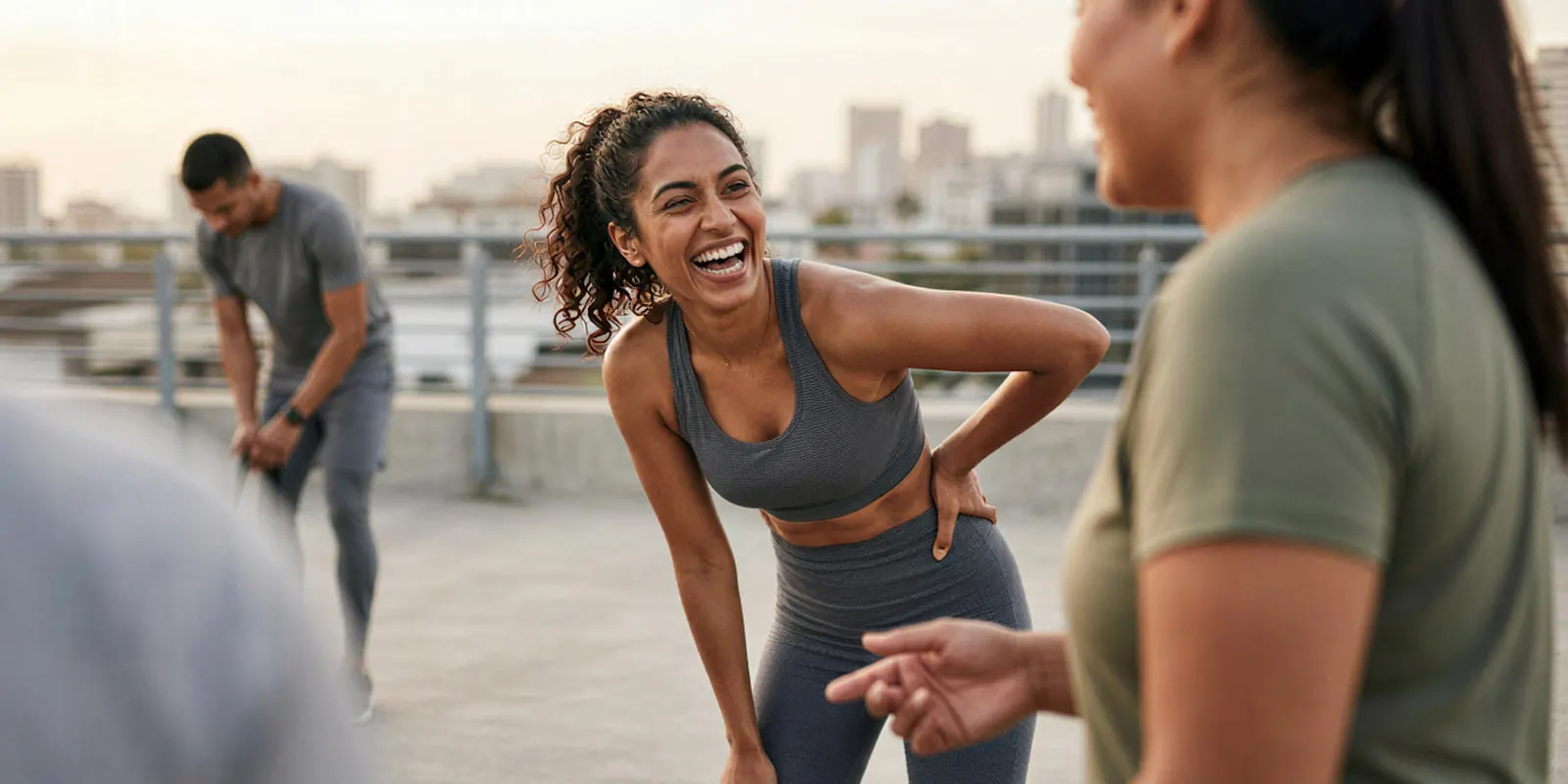 Woman in gray activewear laughing with friends on a rooftop, the kind of campaign frame a supplement range can close with