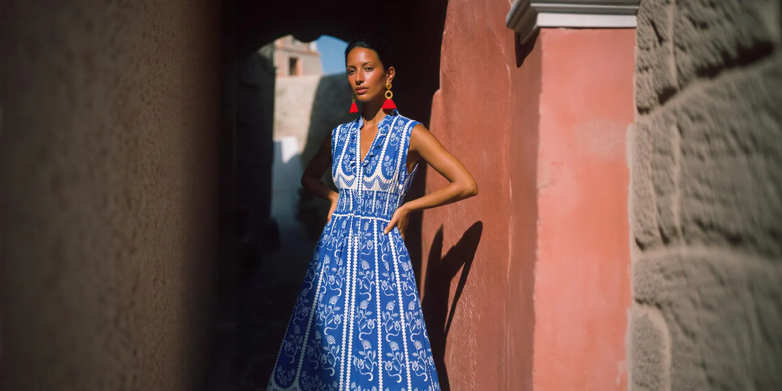 Woman in a blue and white patterned dress stands by a terracotta wall, showing how color, pattern and shape look on a body