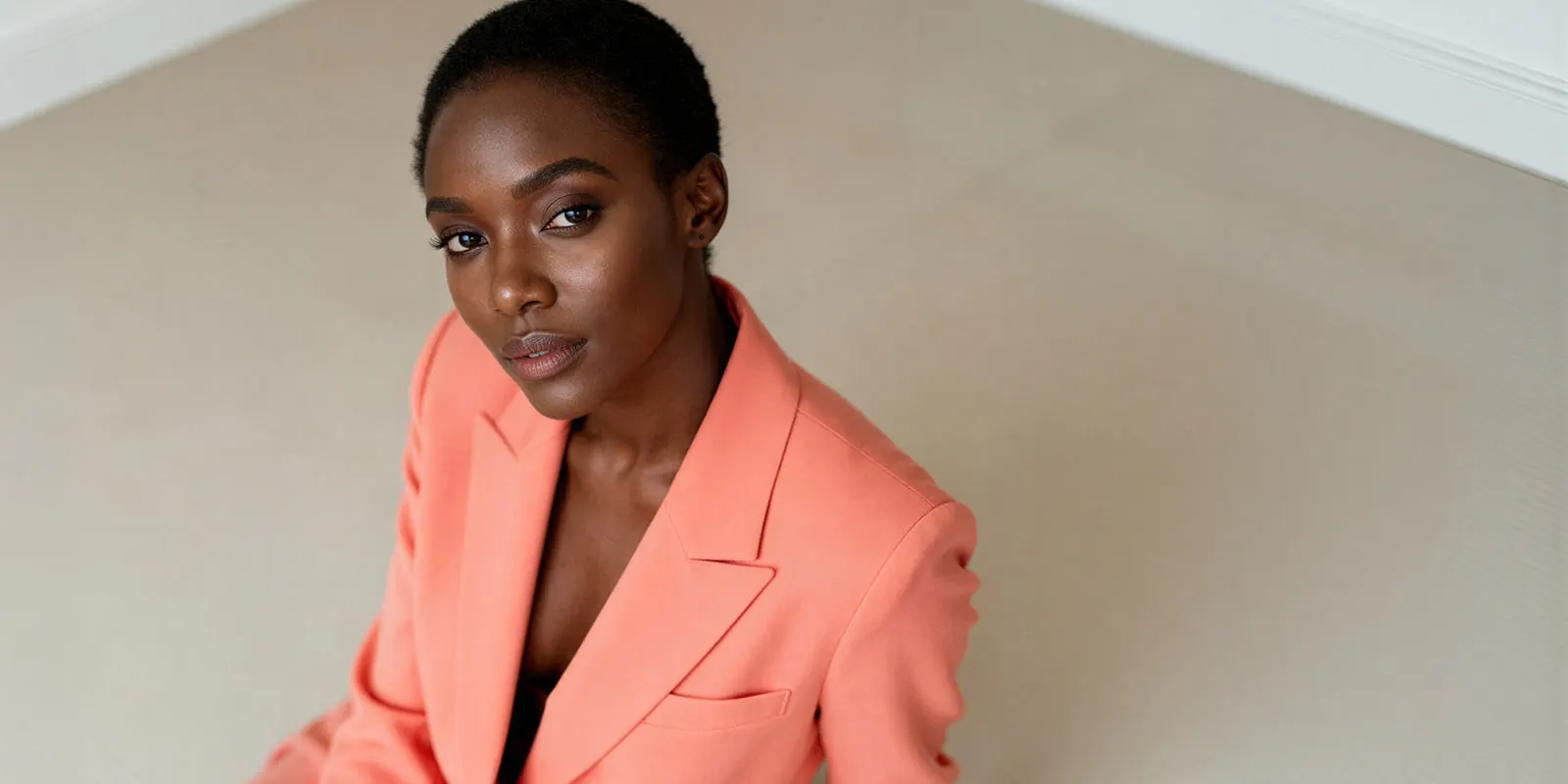A woman in a tailored coral blazer with sharp lapels, a structured garment that needs a graded pattern for each size