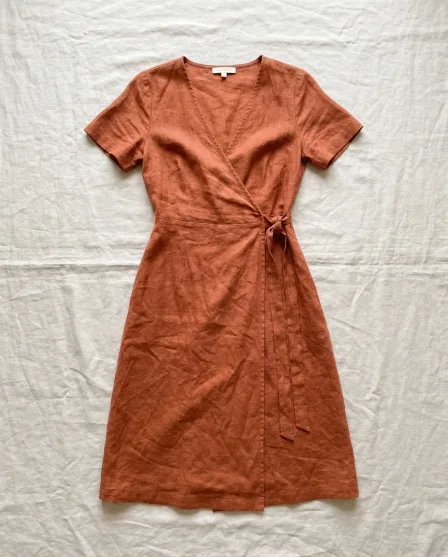A rust wrap dress laid flat on linen. The dress on a model, front and back, in a studio. The same model in the same dress, scene