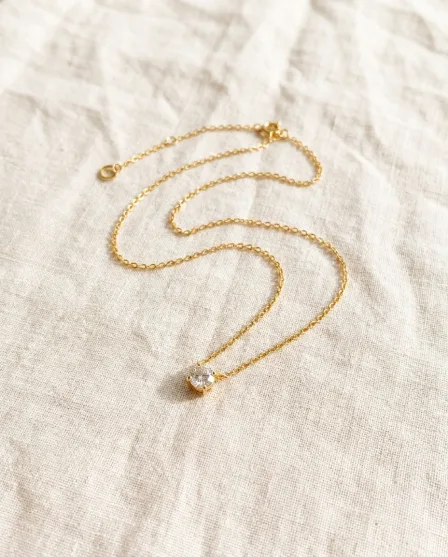 A gold chain laid flat, then the chain worn by a smiling woman and a close detail of the pendant