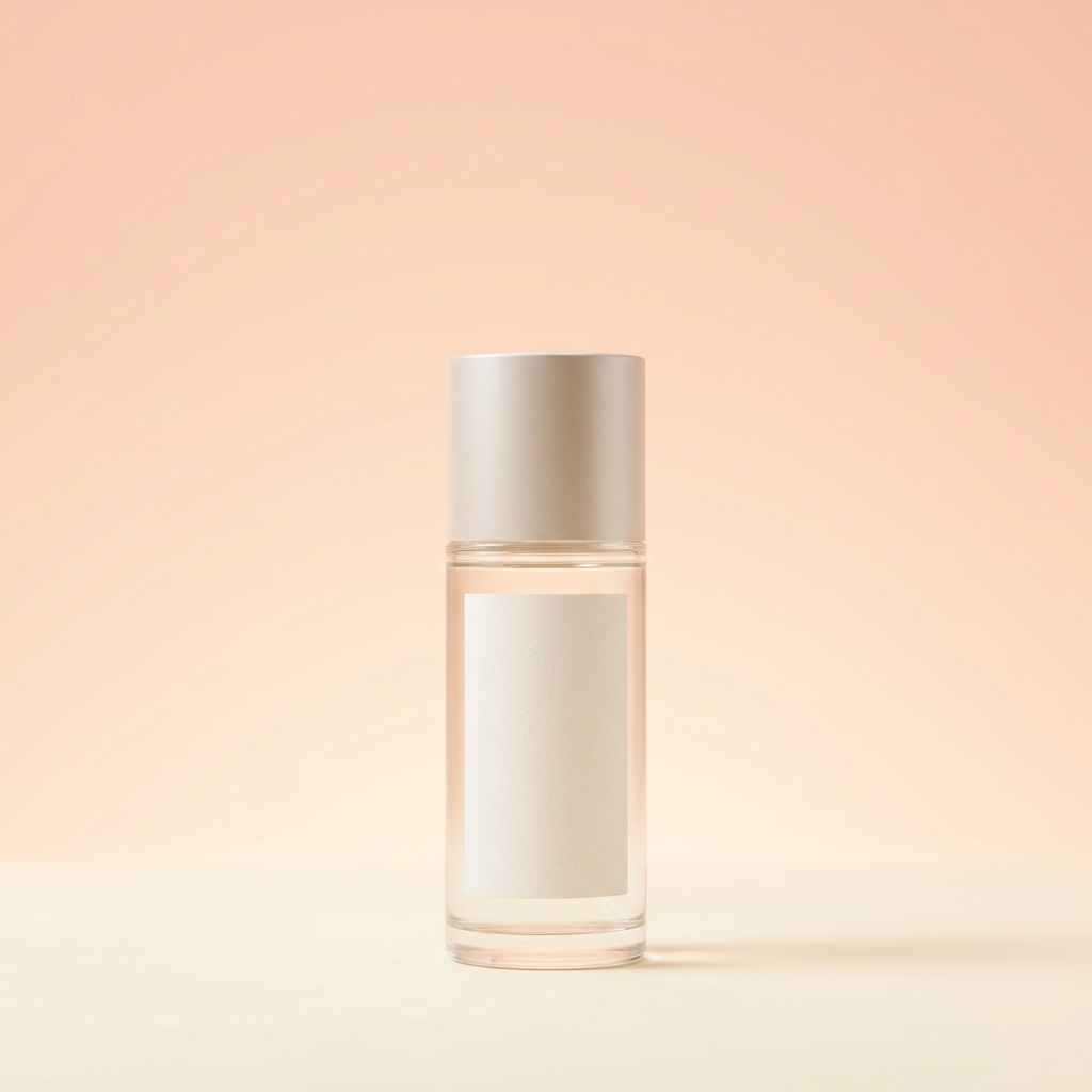 Glass cosmetic bottle with a blank label, standing on a backdrop that shades from soft peach to pale cream.