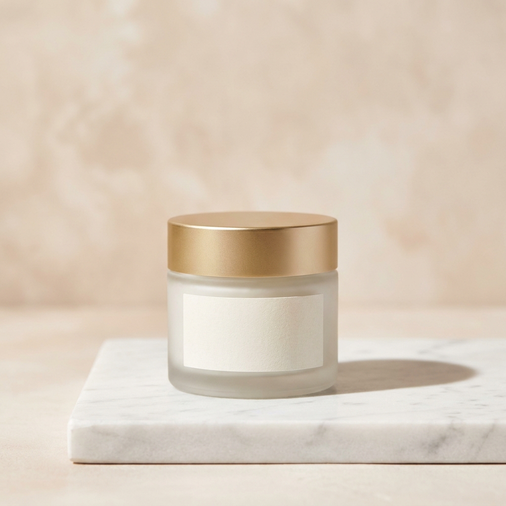 Frosted glass skincare jar with a matte gold lid on a honed white Carrara marble slab with soft grey veining